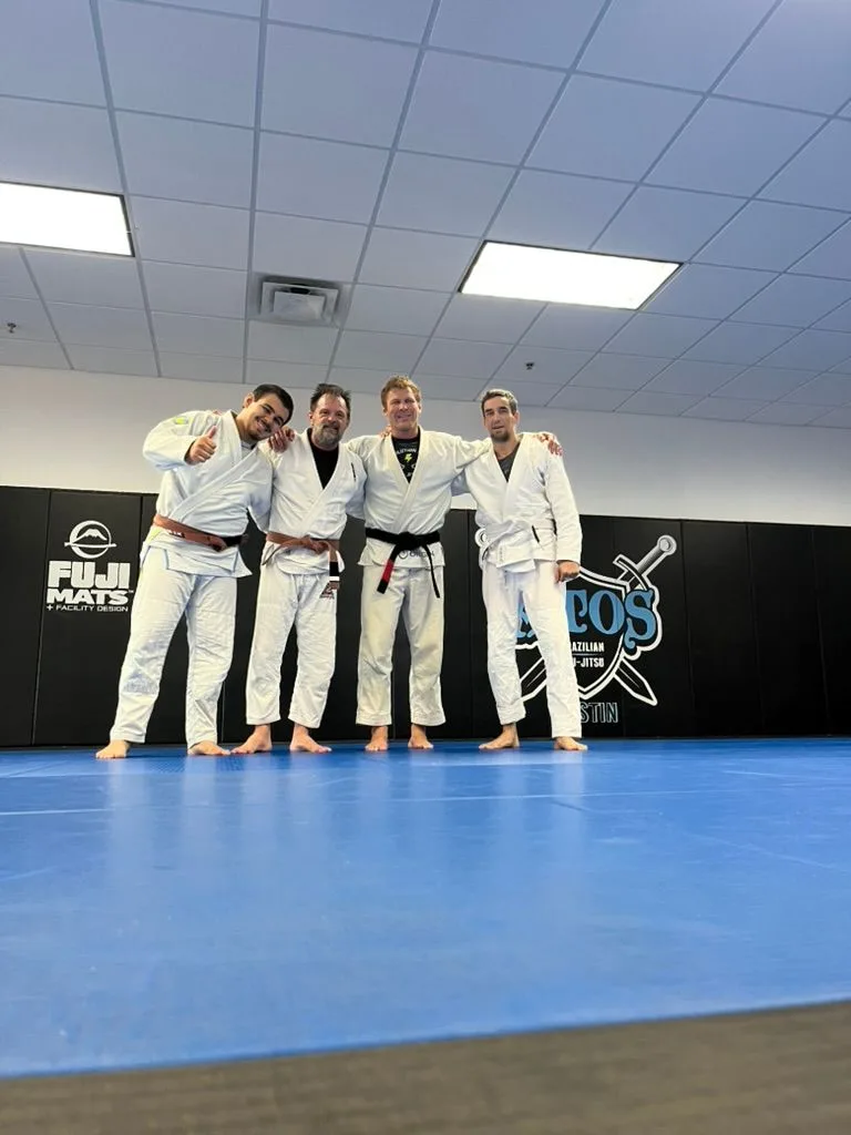 Four training partners in gis on the mats after class at Atos Jiu-Jitsu Austin