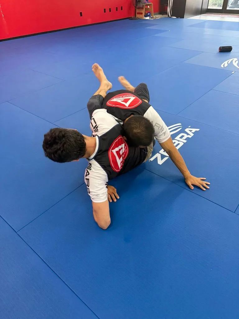 Drilling top pressure and breaking down a partner's base during no-gi practice at Gracie Barra North Austin